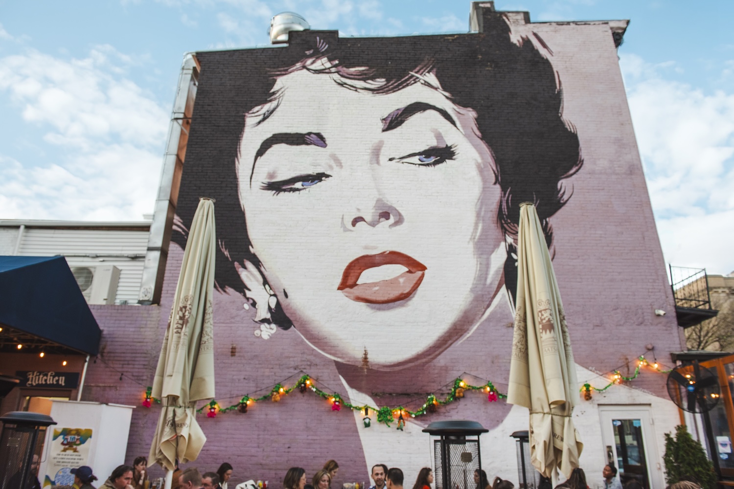 mural of woman with black hair, pink background, umbrellas