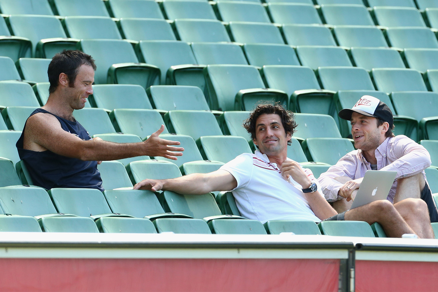 Hamish Blake and Andy Lee sitting in the stands of a rugby stadium.