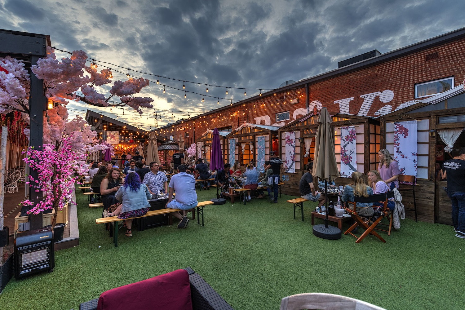 brick wall with benches and umbrellas, people sitting, cherry blossoms