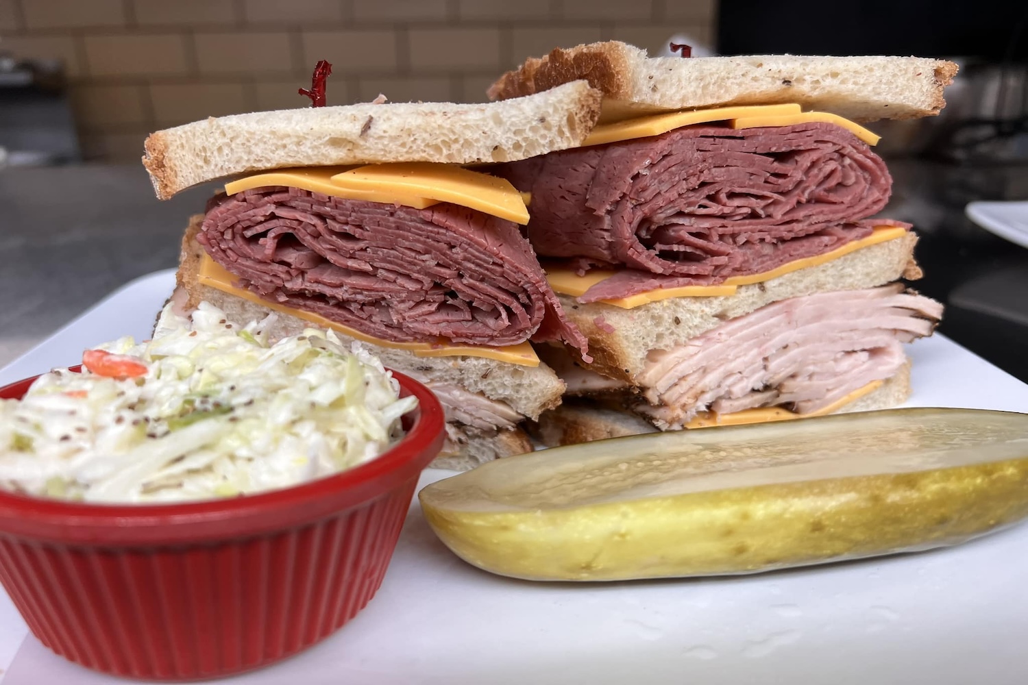 cheese and meat sandwich, coleslaw and pickle on side