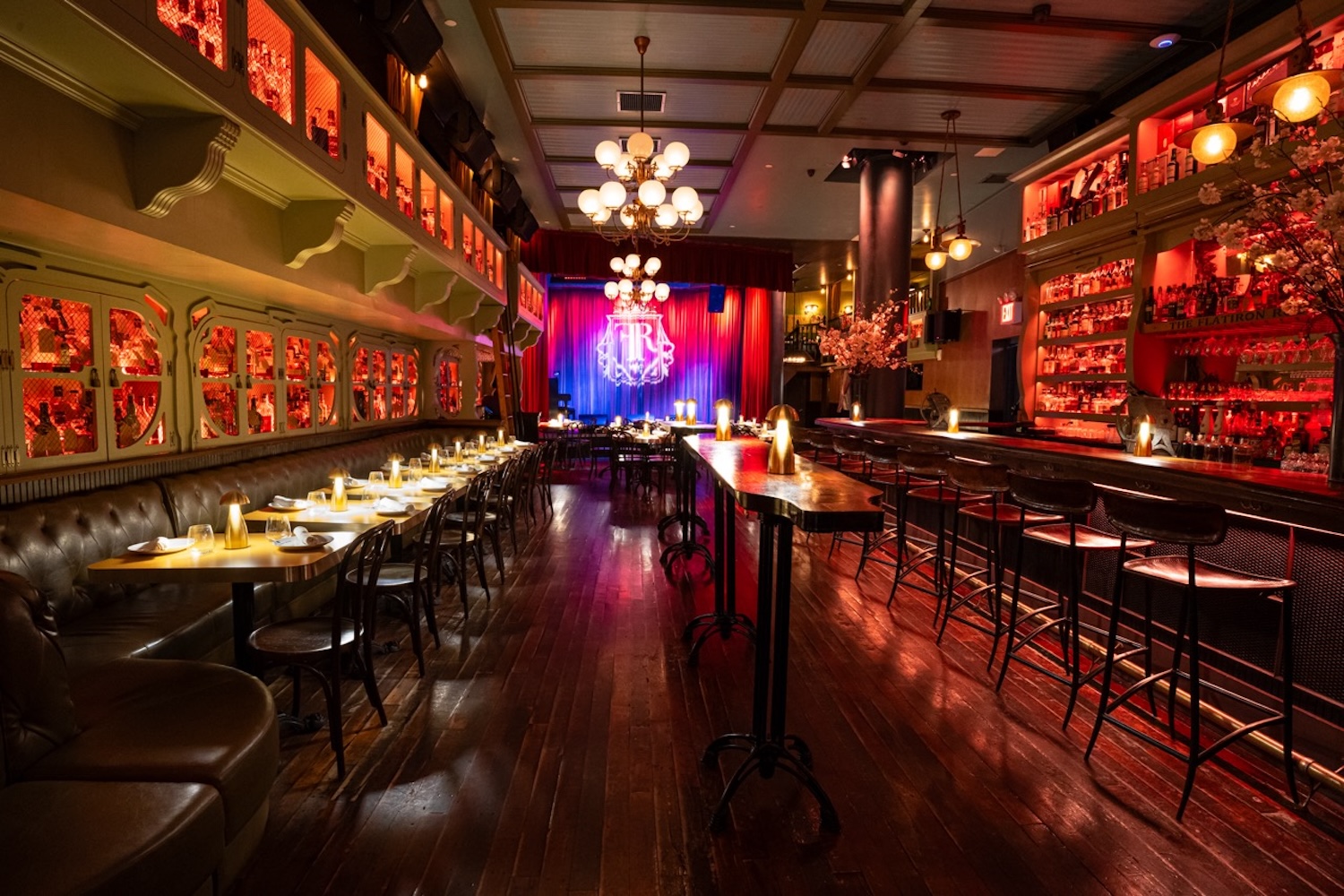 bar with stools and tables, stage with lights on, lights on ceiling