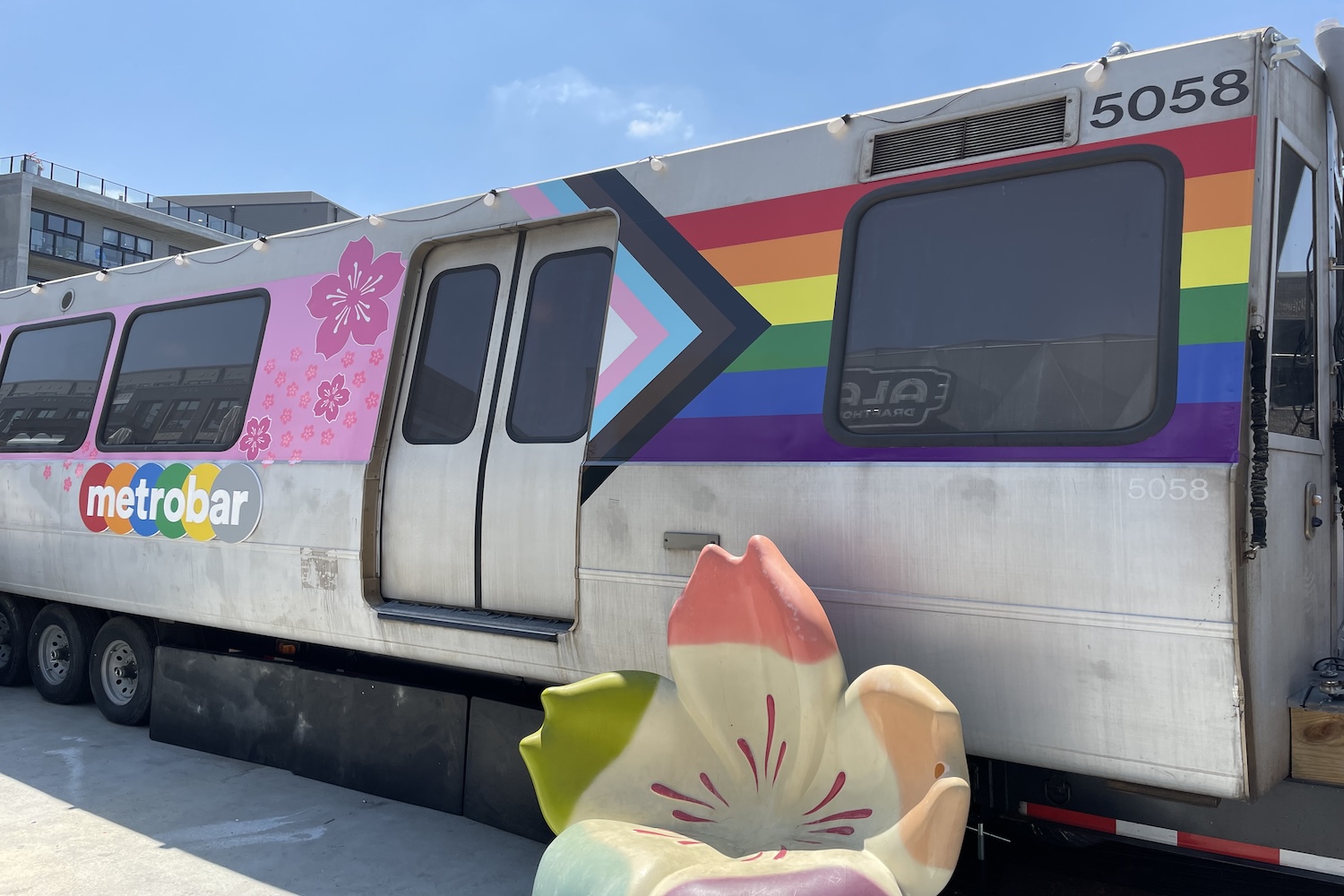 van with pride flag and pink flowers on it, flower shaped chair in front of van