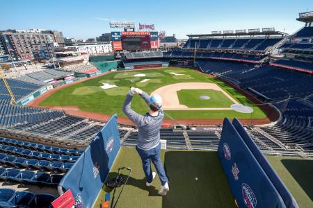 Man swinging golf club over Nationals Park Stadium